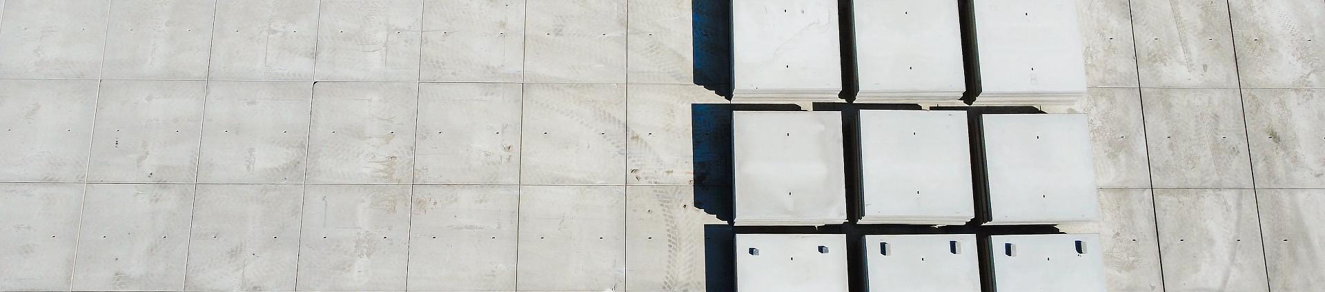 Stapels betonplten in verschillende soorten en maten langs de zijkant van het pand.